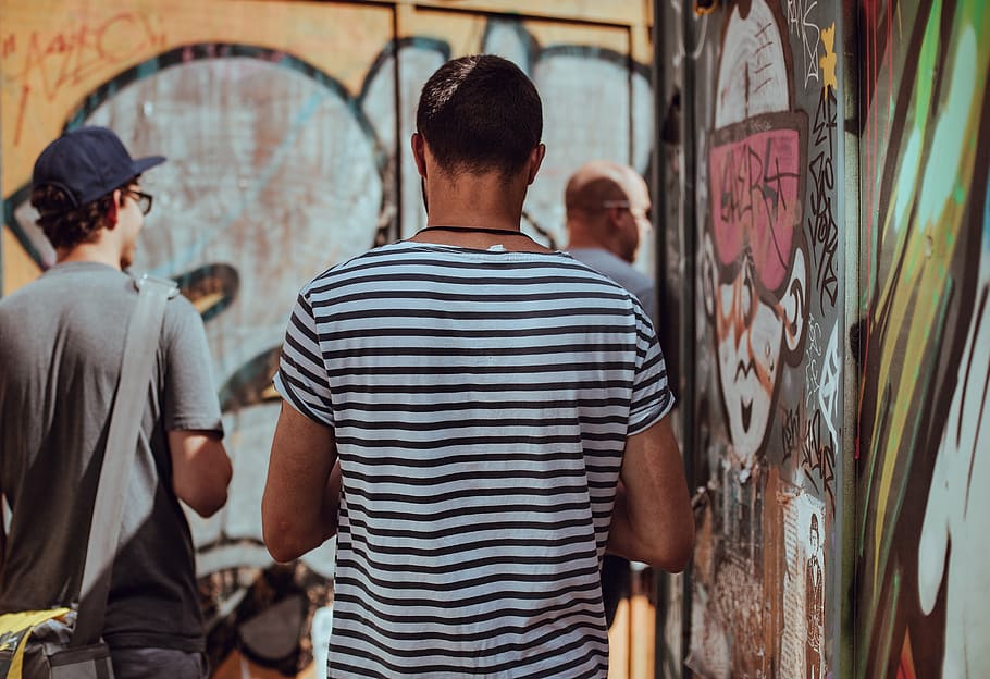 tres, hombres, de pie, al lado, pared de graffiti, durante el día, personas, espalda, chicos, caminando