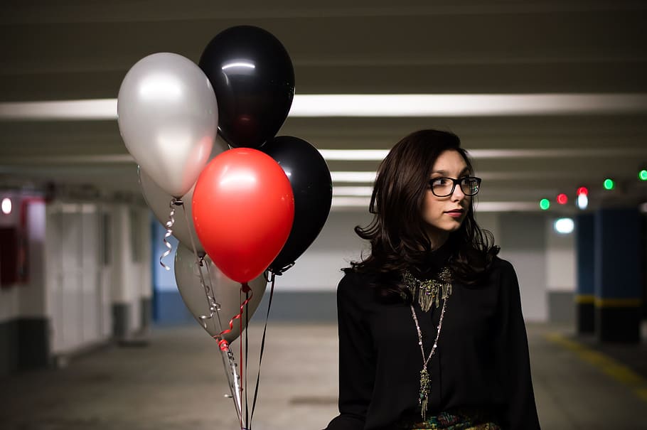 woman, wearing, eyeglasses, black, top, holding, balloons, parking lot, helium balloons, red balloon