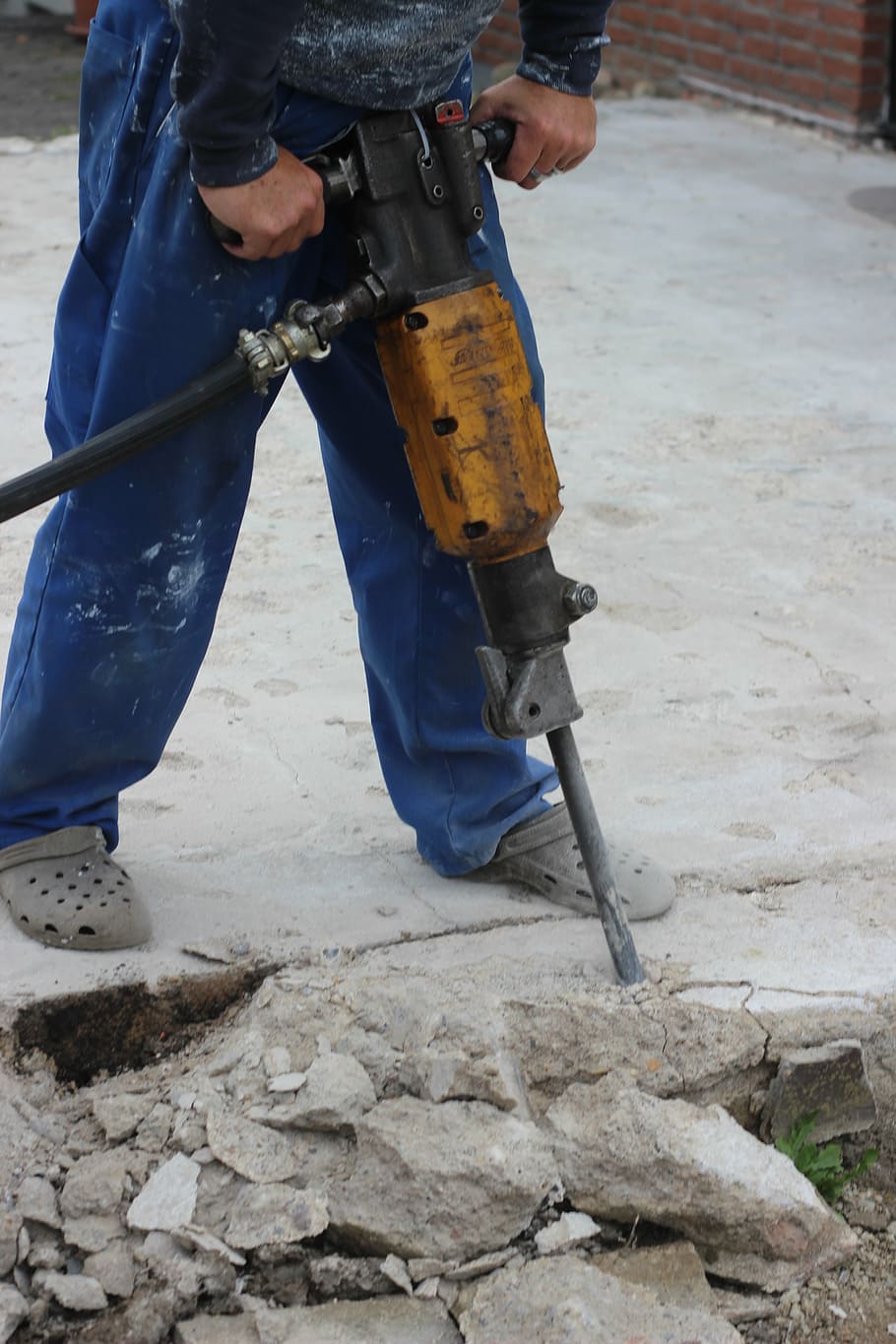person demolishing floor, hammer drill, site, hilti, smash, destroy, yellow, powerful, road construction, construction
