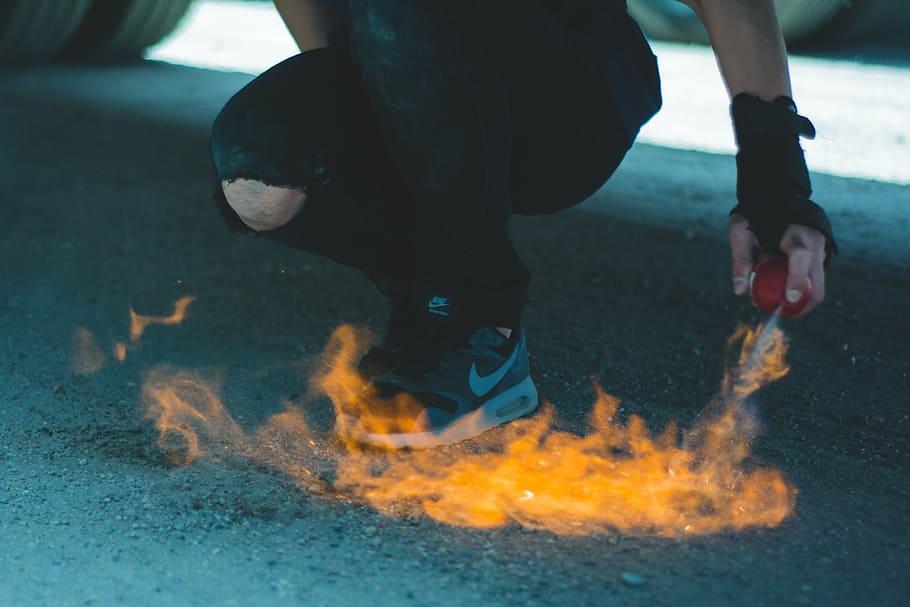 pessoa pulverizando aerossol, fogo, chão, pessoa, vestindo, cinza, sapatos, frente, chamas, spray