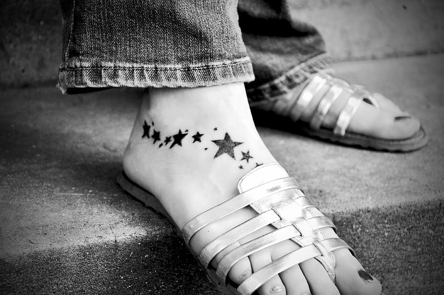 grayscale photograph, person, wearing, flat, sandals, tattoo, foot, skin, black and white, stars