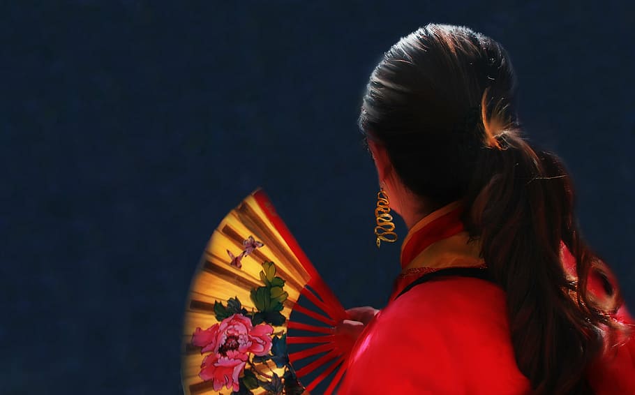 mujer ', sosteniendo, floral, plegable, abanico, mujer, rojo, oro, cabello, cola de caballo