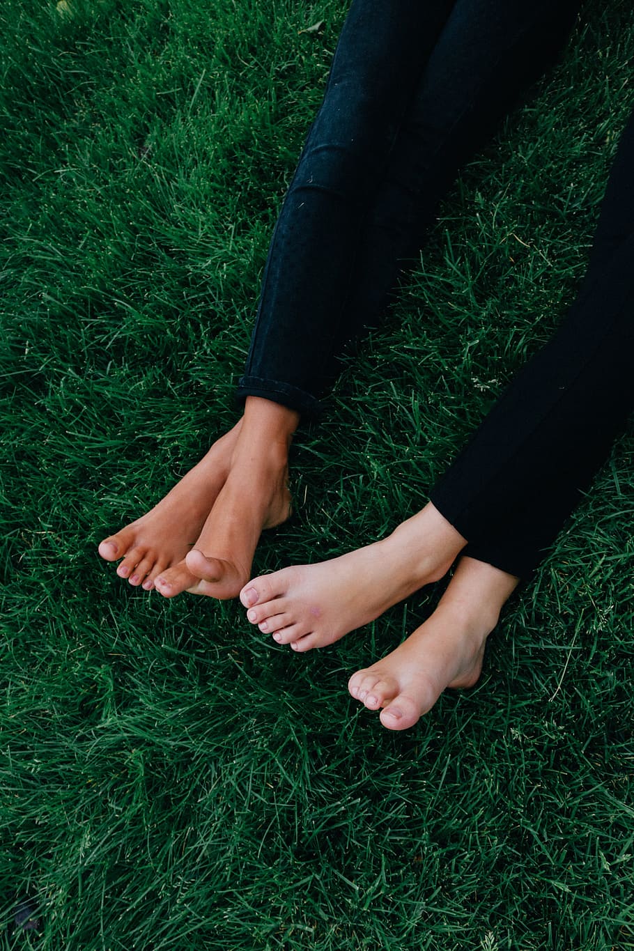 two, person, lying, green, lawn grass, wearing, black, denim jeans, feet, grass