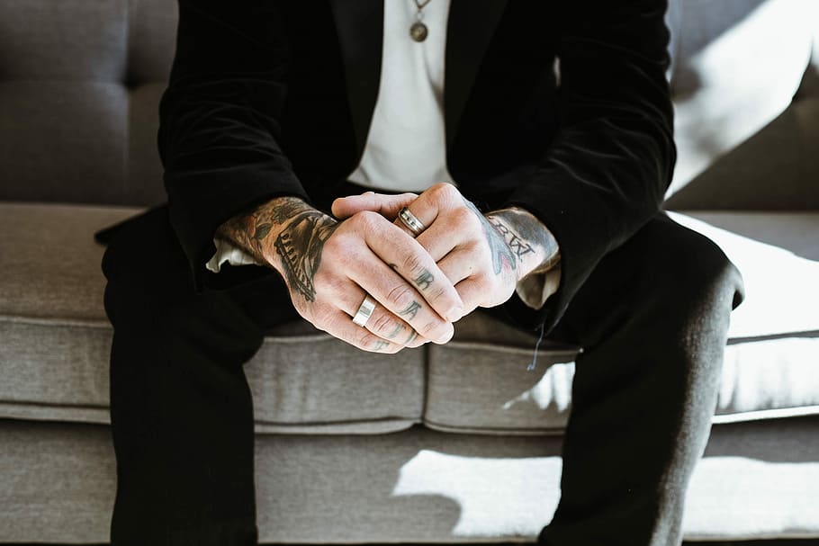 man, wearing, black, formal, attire, two, rings, sitting, gray, couch