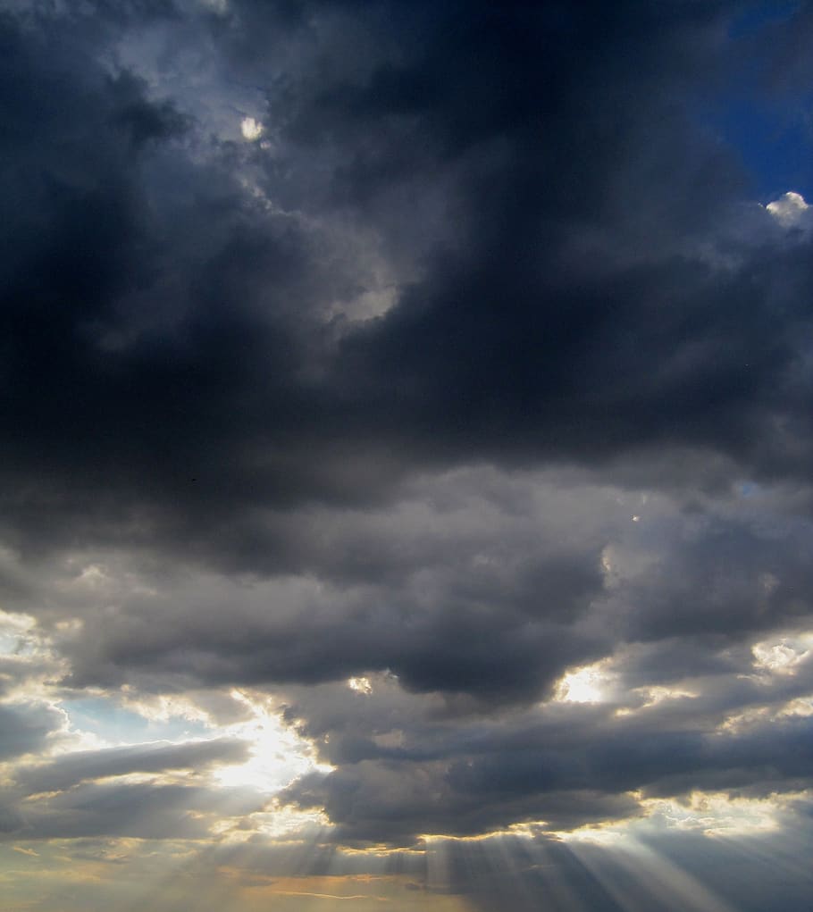 clouds, heavy, dark, sky, ink color, dense, light, smudge of yellow-orange, sun rays, crepuscular rays