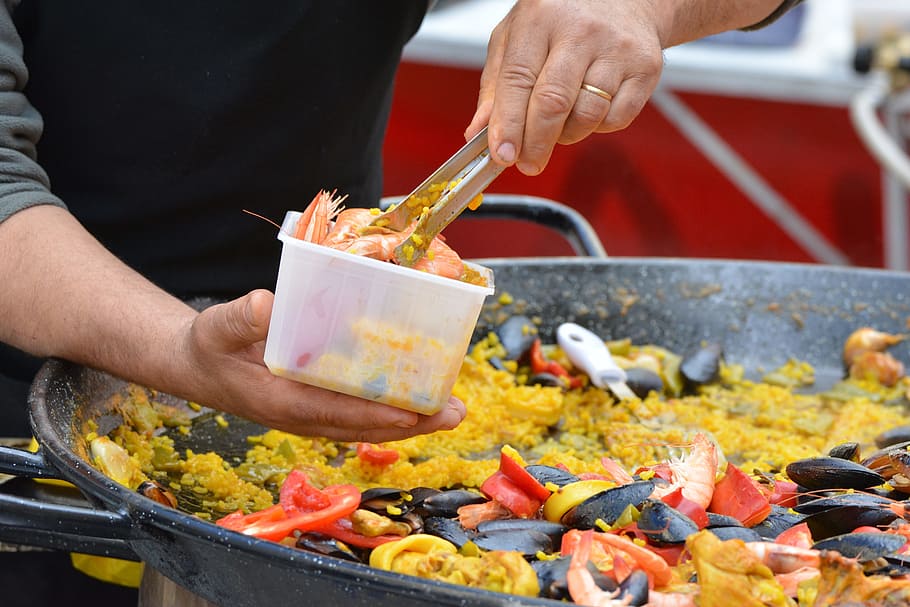 person, holding, gray, thong, clear, plastic container, daytime, paella, power supply, food