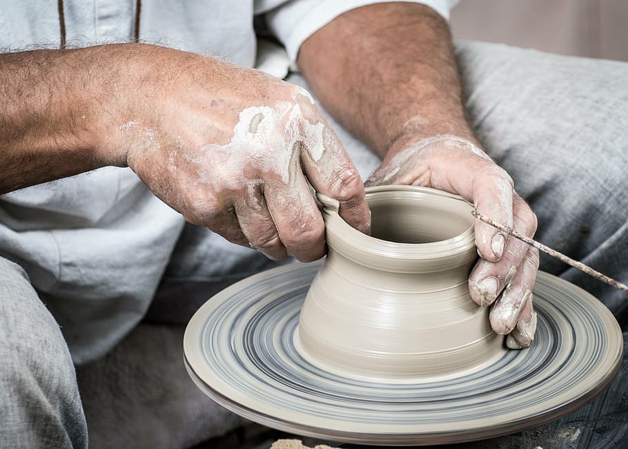 person, gray, shirt, pants molding clay pot, potter, ceramics, clay, circle, potter's wheel, hands