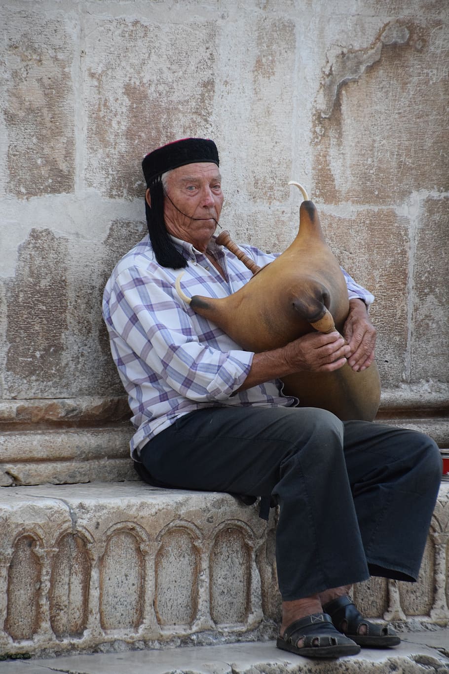 bagpipe, man, croatia, sitting, real people, one animal, mammal, one person, lifestyles, wall - building feature