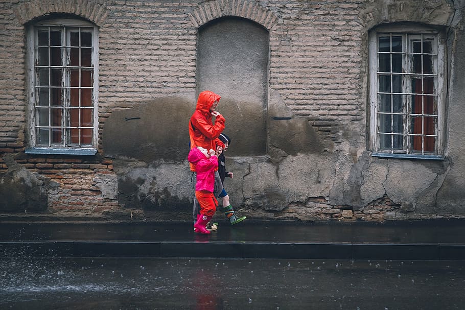 person, wearing, red, rainy, coat, his/her, /her children, walking, black, asphalt road