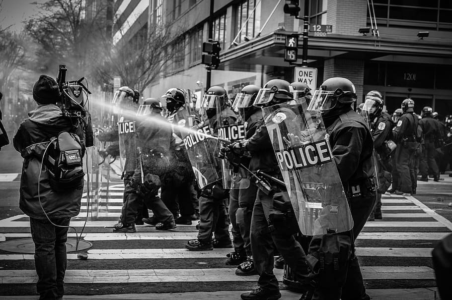 grayscale photography, police, shields, stands, pedestrian, lane, people, protest, water, shield