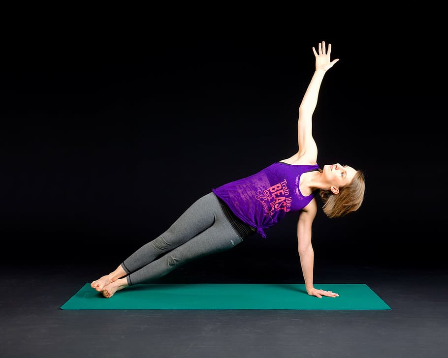 Mujer, vistiendo, púrpura, tanque, top, gris, polainas, posición de yoga, verde, estera de yoga