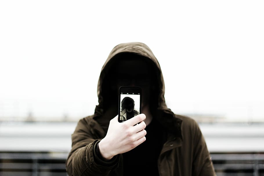 person, holding, phone, wearing, brown, hoodie, people, one Person, outdoors, urban Scene