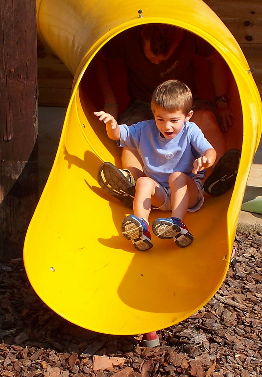 wearing, blue, crew-neck shirt, sitting, yellow, metal slide pipe, Playground, Child, Slide, Boy