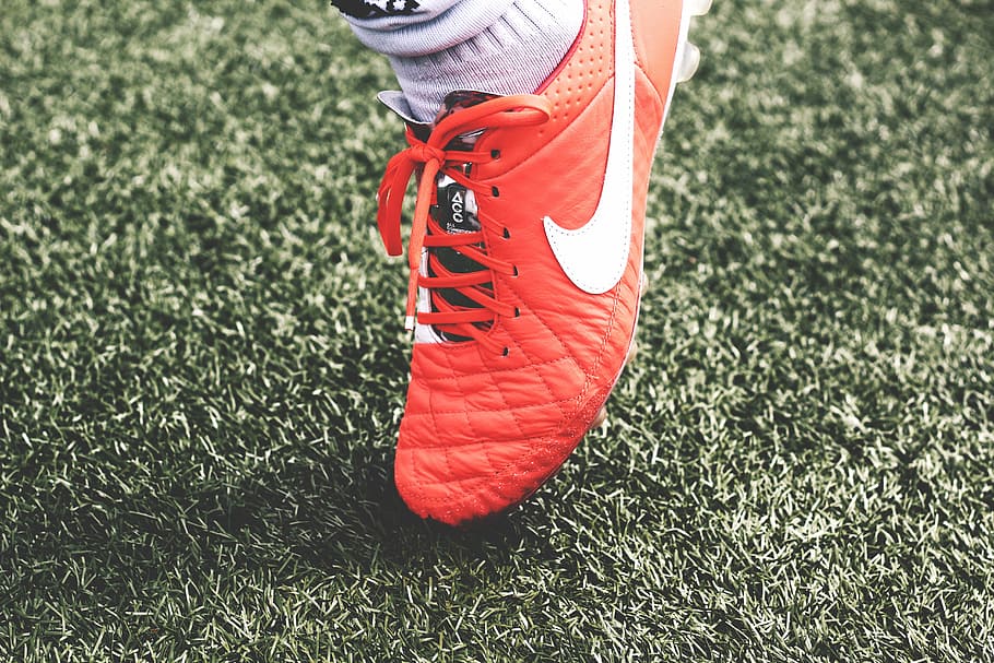person, wearing, quilted, red, nike cleat, unpaired, nike, cleat, grass, soccer
