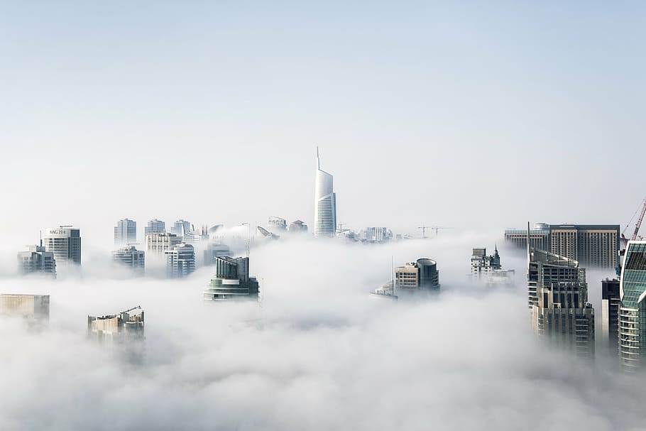 city buildings, surrounded, clouds, daytime, building, structure, sky, infrastructure, window, tower