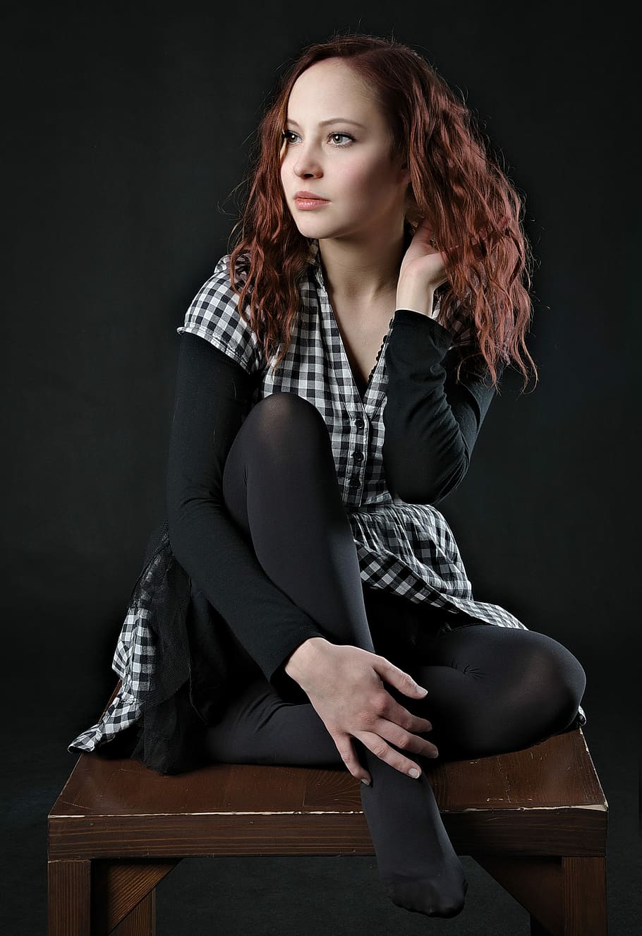 woman, wearing, black, white, checkered dress, sitting, brown, wooden, table, girl