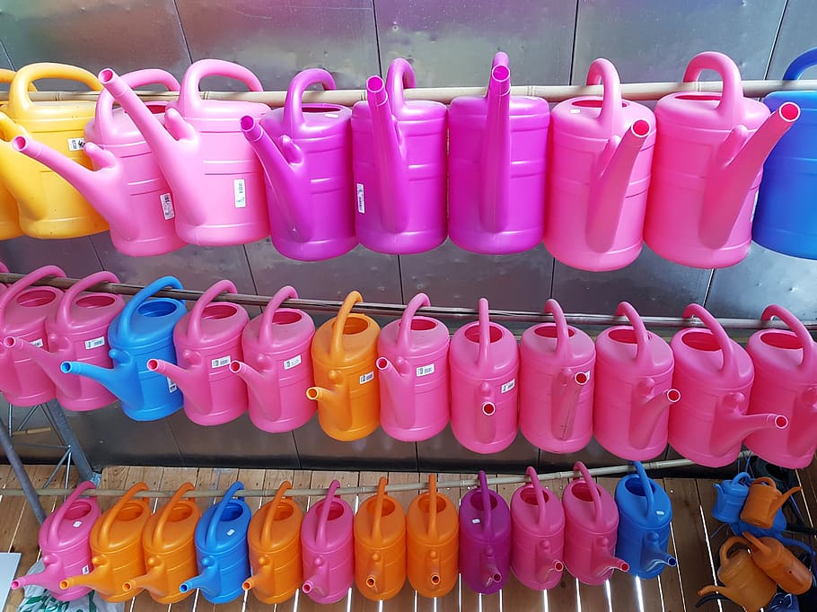 watering cans, sale, lined up, plastic, goods, colorful, yellow, pink, blue, orange