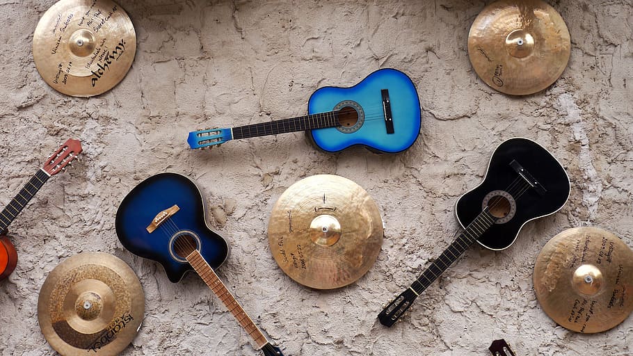 three, assorted-color, acoustic, guitars, surrounded, cymbals, wall, decoration, indoors, blue