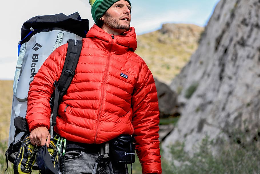 man, wearing, red, bubble jacket, gray, backpack, standing, rock, people, guy