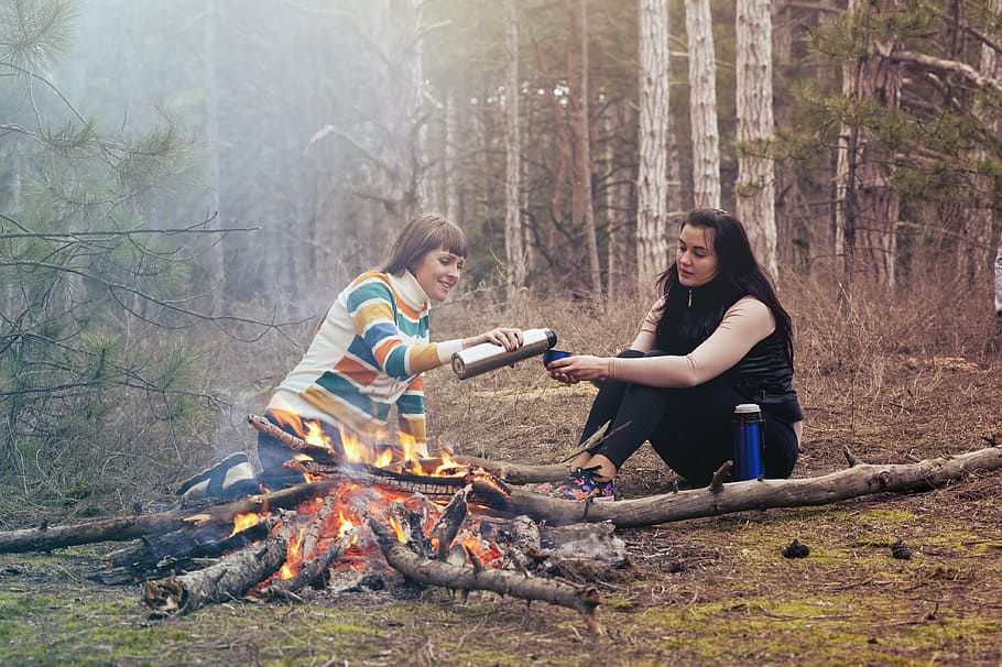 woman, holding, vacuum flask, pouring, liquid, cup, sitting, soil, firepit, women