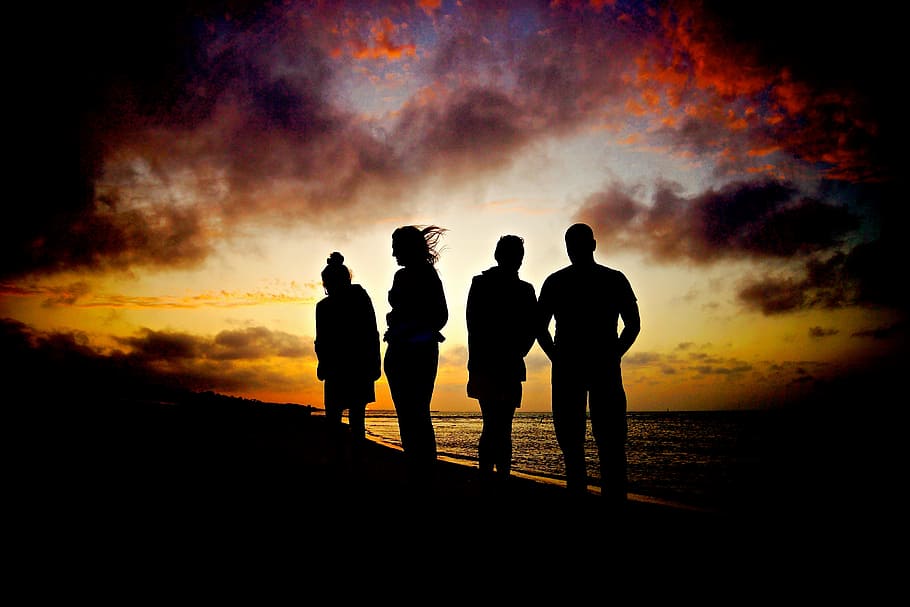 silueta, cuatro, personas, de pie, orilla del mar, hacia, vista del atardecer, puesta de sol, playa, siluetas