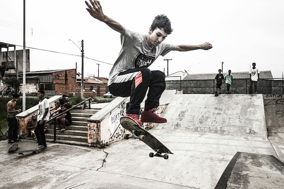 boy, playing, skateboard, ollie, man in gray, crew-neck, t-shirt, black, pants, red