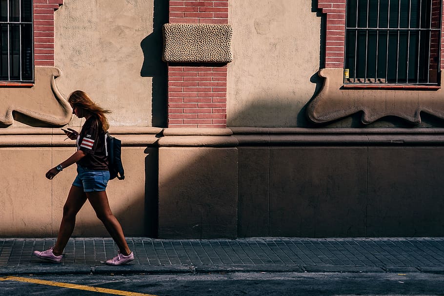 woman, walking, sidewalk, wearing, black, shirt, blue, shorts, street, daytime