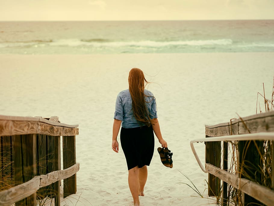 woman, holding, pair, sandals, walking, sand, blue, sleeve, shirt, black