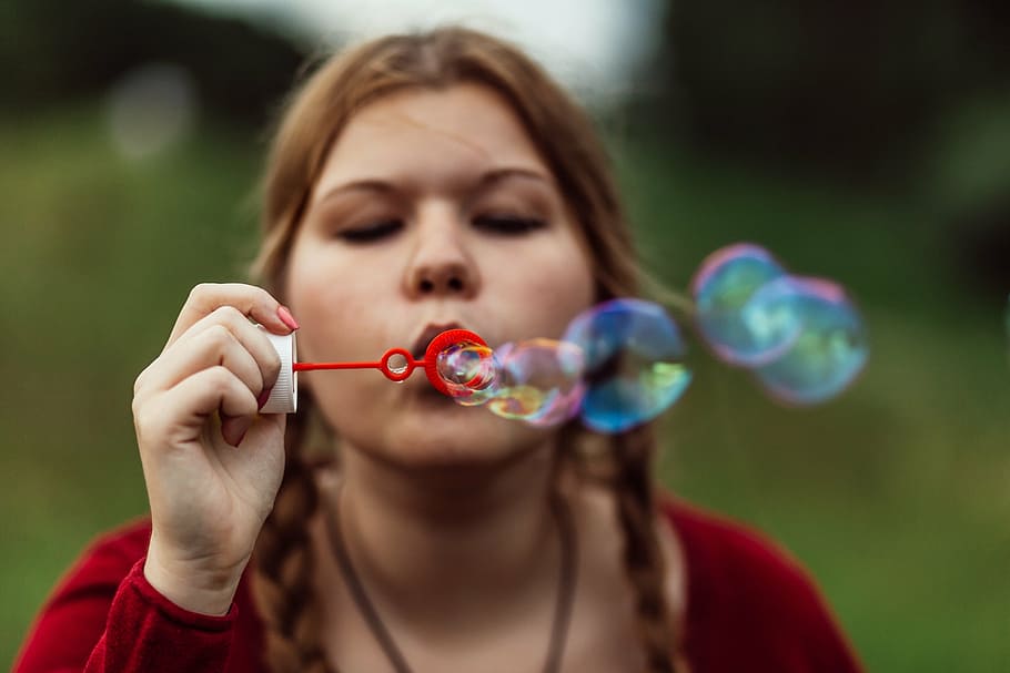 woman, wearing, red, crew-neck, long-sleeved, shirt, holding, bubble toy, soap bubble, girl