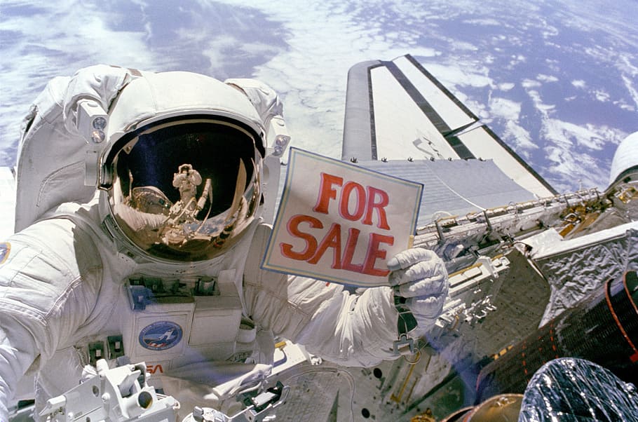 person, wearing, astronaut suit, holding, sale signage photography, space shuttle astronaut, discovery, spaceship, space walk, satellite recovery