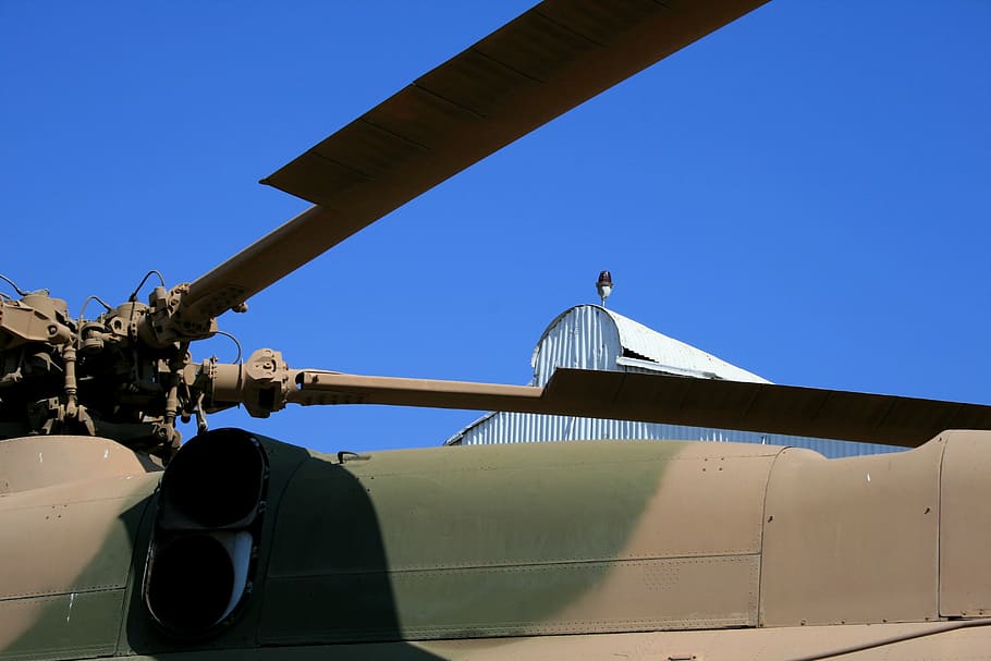 blue sky, roof of helicopter, blades of helicopter, clear sky, camouflage paint scheme, brown and green, military craft, museum, transportation, mode of transportation