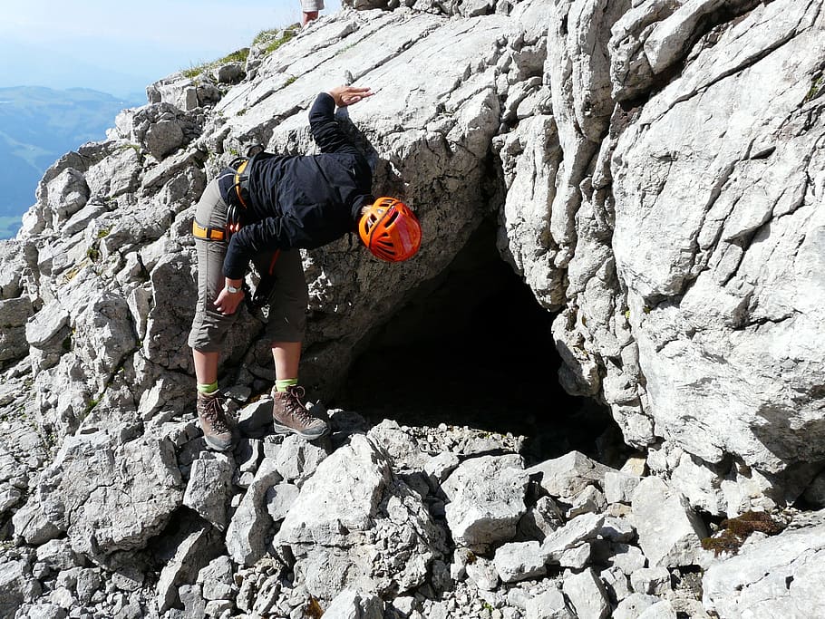person, wearing, orange, bicycle helmet, peeping, inside, cave, emergency shelter, bivouac place, bivouac