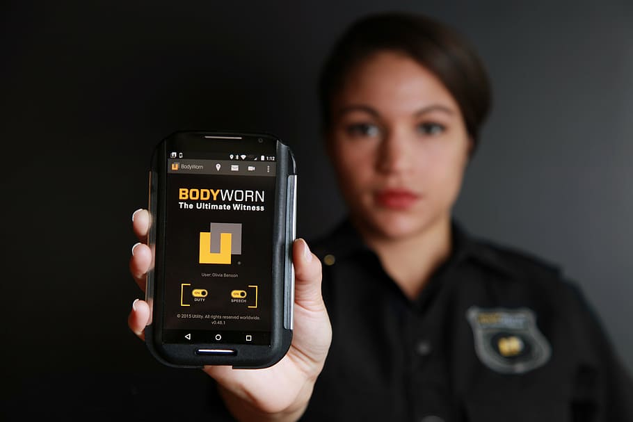 woman, holding, smartphone, displaying, bodyworn, body camera, police body camera, law enforcement, cops, law enforcing
