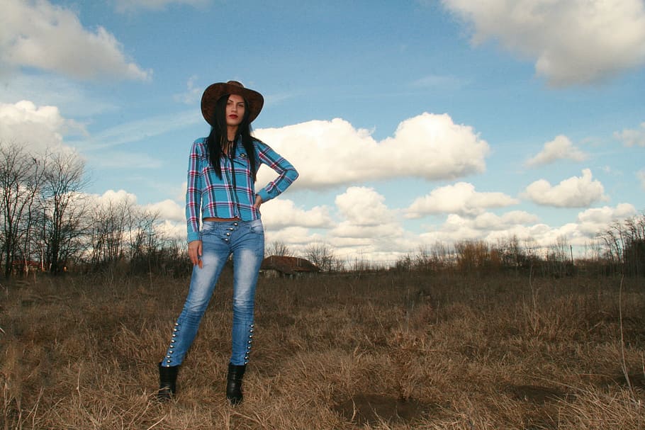 mulher, vestindo, azul, xadrez, camisa esporte, chapéu de cowboy, em pé, campo, vaqueira, ocidental