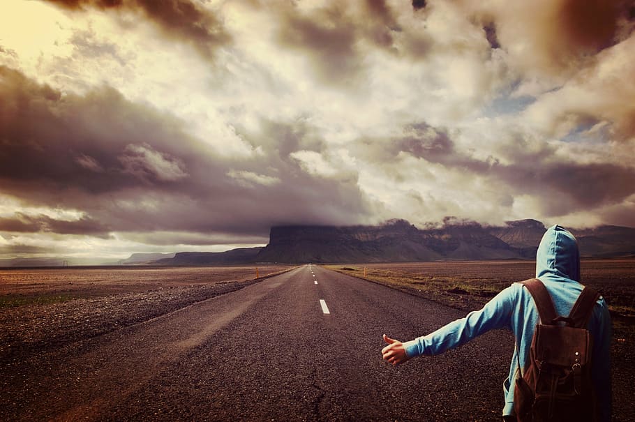person, wearing, blue, hoodie, standing, gray, pavemnet, road, man, hitcher