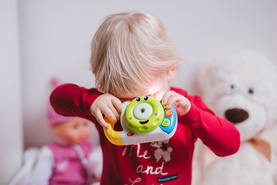 close-up photo, boy, covering, eyes, holding, plastic toy, people, baby, blonde, camera