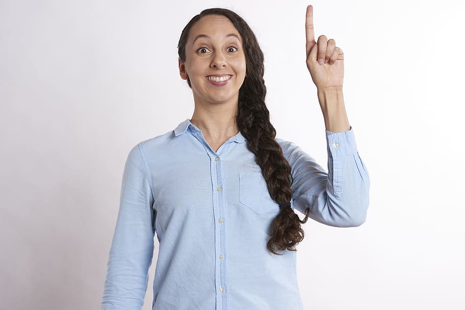 woman, wearing, blue, button-up long-sleeve shirt, standing, wall, idea, finger, point, creative