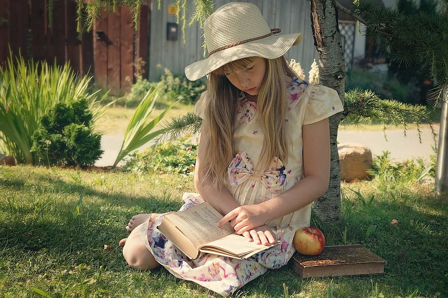 woman, yellow, floral, dress reading book, brown, tree, sunhat, red, honeycrisp apple, girl