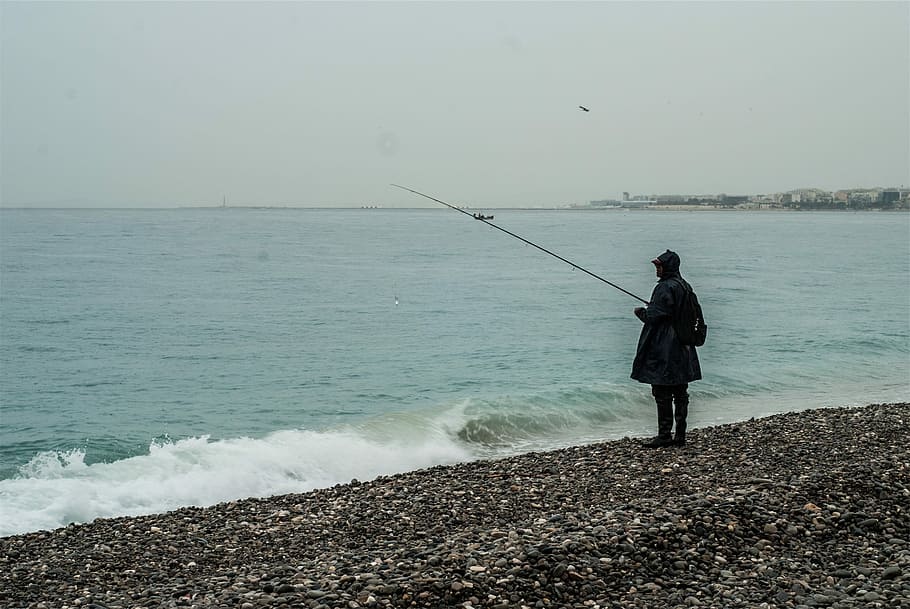 Fishing, Fisherman, Beach, Rocks, pebbles, waves, water, rain jacket, boots, raining