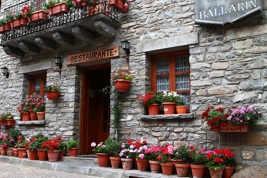 restaurante signage, restaurant, european restaurant, flowers in pots, begonia, begonia in pots, storefront, rock wall, rock building, stone building