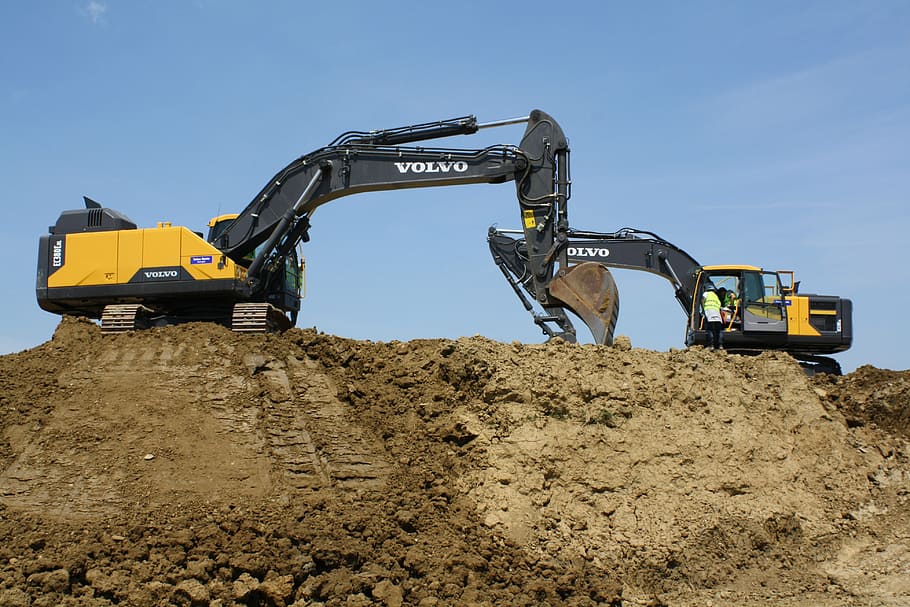 two, yellow-and-black volvo excavators, brown, sand, blue, sky, building, buildings, earthmoving, excavators