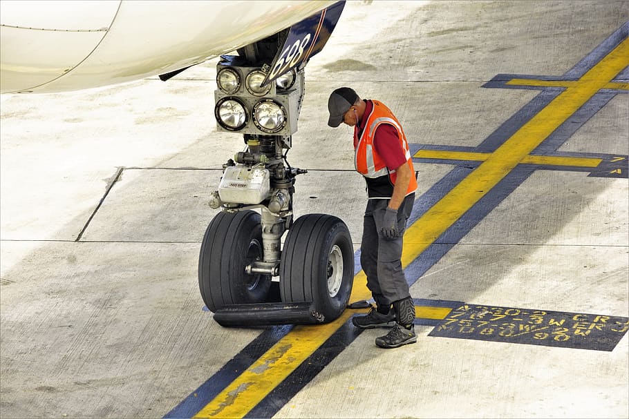 landing gear, nose wheels, commercial, airliner, gate, worker, setting, wheel blocks, chocks, aircraft