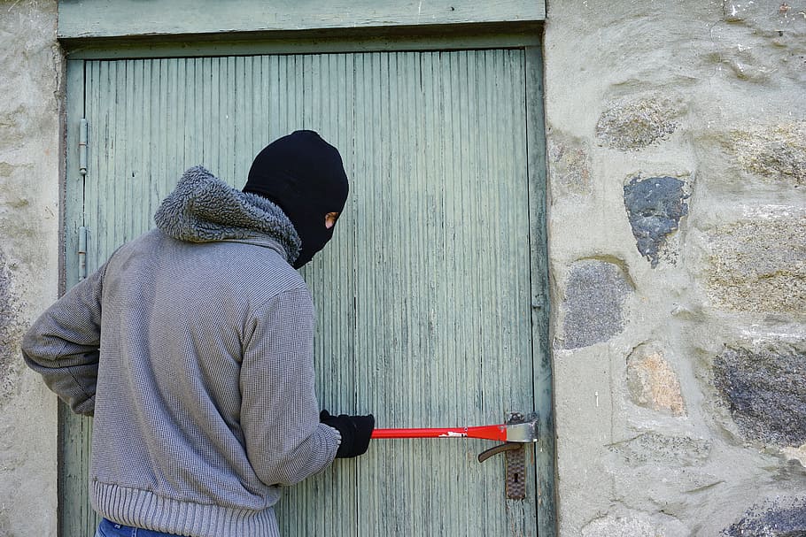 hombre, vistiendo, gris, chaqueta con cremallera, sosteniendo, rojo, herramienta de mano, al lado, puerta, ladrón