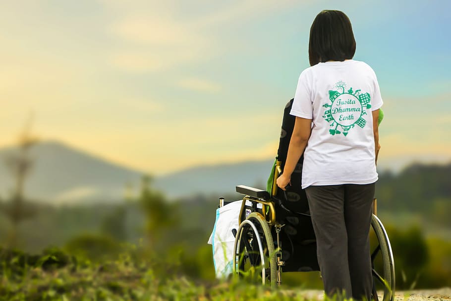 woman, white, t-shirt, holding, black, self-propelled wheelchair, hospice, caring, nursing, elderly