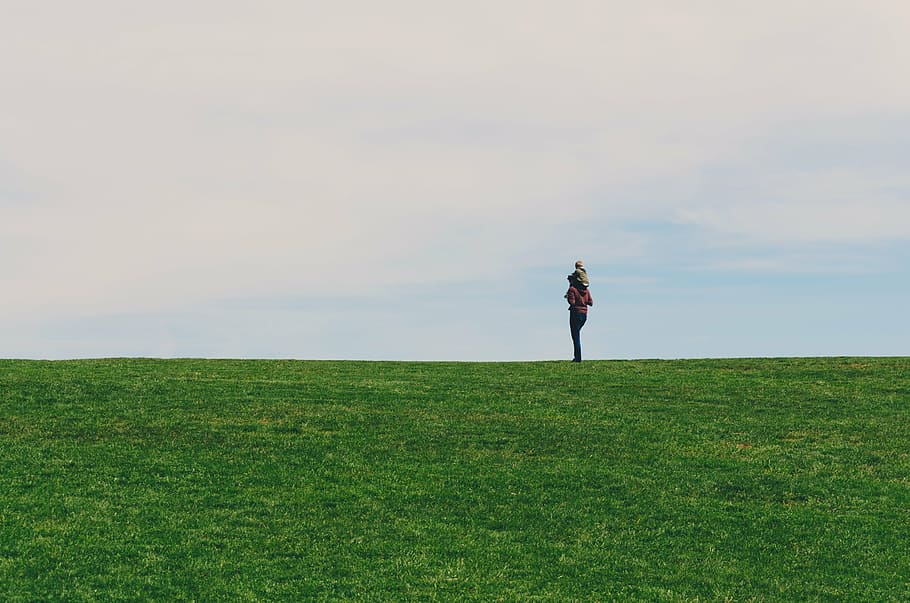person, standing, grass field, daytime, people, alone, travel, adventure, green, clouds