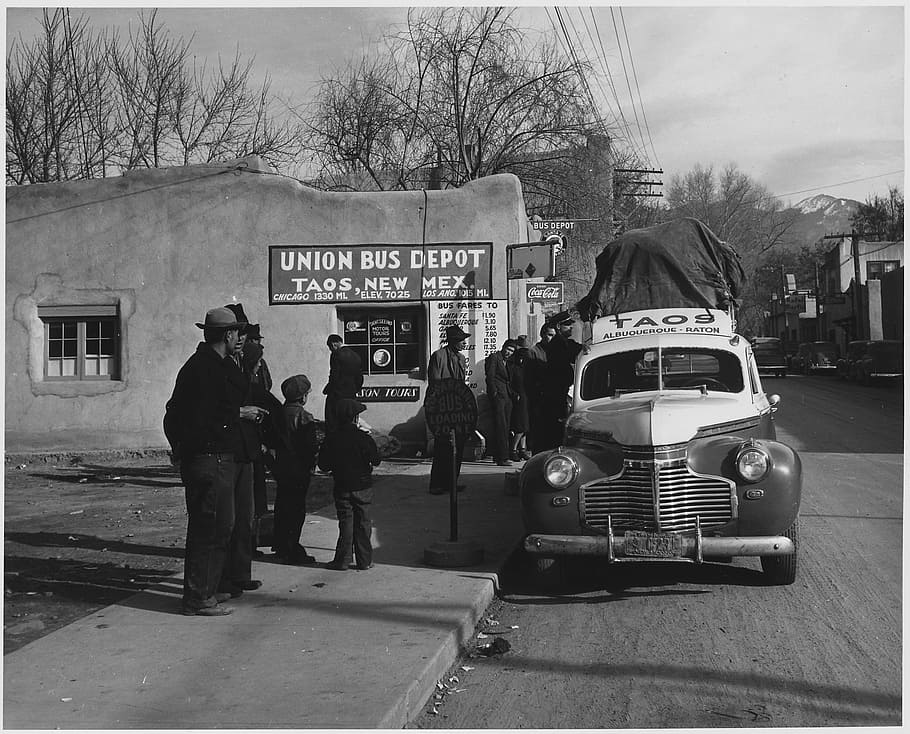 grayscale photo, people, sidewalk, taos, new mexico, 1941, black and white, bus depot, station, building