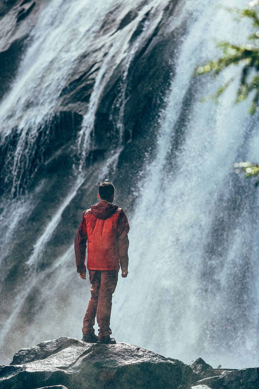 Hombre, vistiendo, rojo, chaqueta rompevientos con capucha, de pie, gris, roca, mirando, cascadas, durante el día