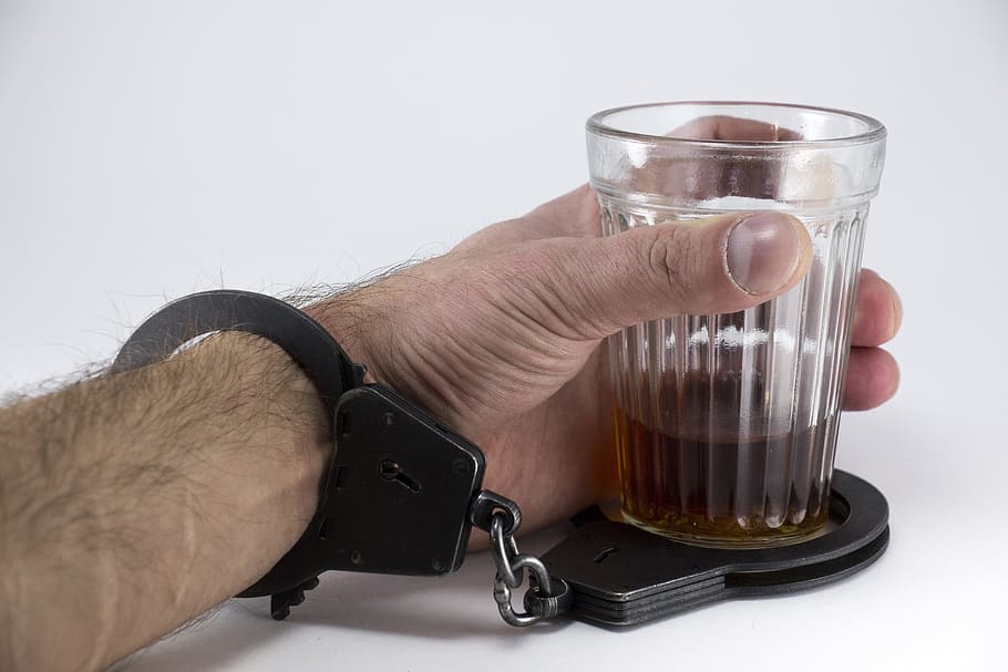 person, wearing, black, handcuff, holding, clear, glass cup, Alcohol, Glass, Hand