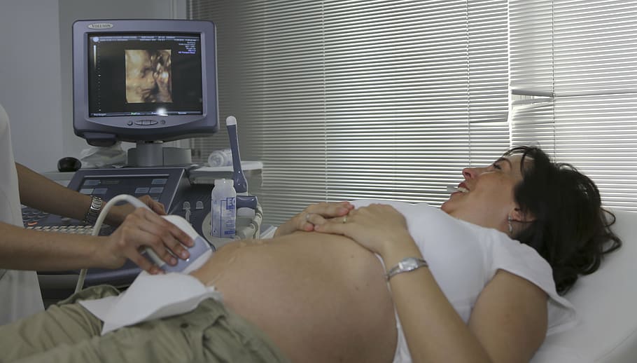 woman, undergoing, ultrasound, wearing, white, shirt, grey, bottoms, laying, mattress