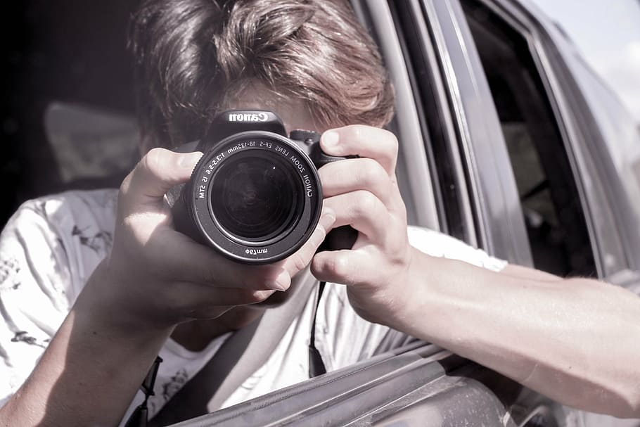 person, holding, dslr camera, inside, car, daytime, selfie, about us, shot, us